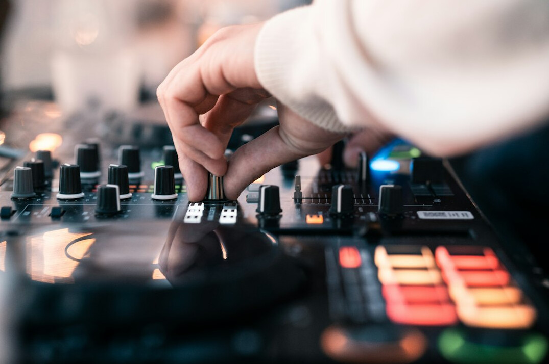 Close-up of hands operating a video vision mixer console with glowing buttons